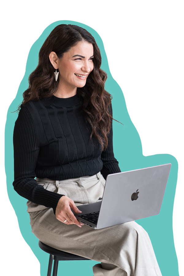 A smiling professional women sitting on a stool with a laptop